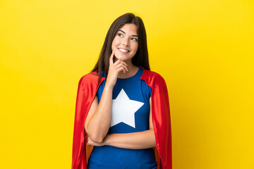 Super Hero Brazilian woman isolated on yellow background thinking an idea while looking up