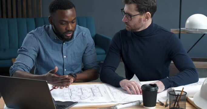Teamwork in modern loft Office of stylish Engineer and Architect. Two Workers on the Construction Company are correcting new Blueprints of Privat House. Teamwork. Start-Up.