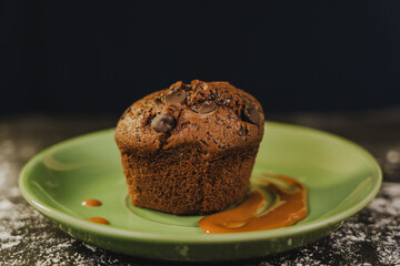 Homemade chocolate chips muffin with caramel on a green dish served gourmet