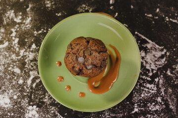 Homemade chocolate chips muffin with caramel on a green dish served gourmet