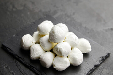 Italian mozzarella cheese balls on black slate board over dark concrete background