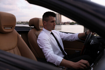 Stylish handsome businessman driving luxury convertible car