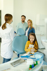 Fototapeta premium Child looks scared and hugging her toy while sitting in dental chair