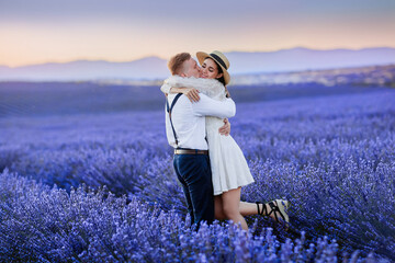 Pretty couple in love in vintage style embraces in the middle of a blooming lavender during a trip and vacation in France