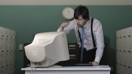 Angry man is destroying old computer with baseball bat in office. - Powered by Adobe