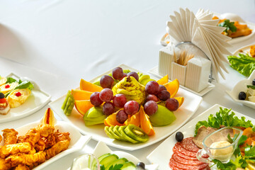 snacks and fruits on a banquet table with a white tablecloth.