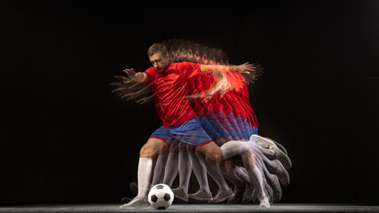 Non stop moving. Young caucasian football soccer player playing in motion in mixed light on dark...