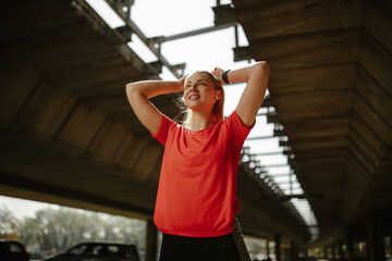 Athletic beautiful woman tying her hair. Sporty woman getting ready for workout.