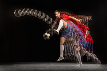 Non stop moving. Young caucasian football soccer player playing in motion in mixed light on dark...