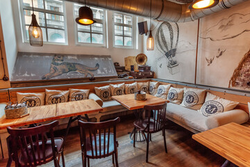 Fancy restaurant original interior with pillows on the sofa and tables with chairs.