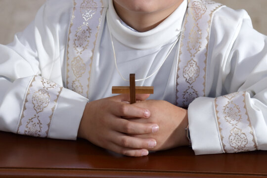 Ragazzo con il crocifisso tra le mani indossa la tunica per prendere il sacramento della comunione