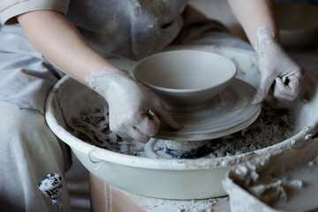 Woman making pottery on spinning wheel in her workshop