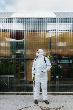 Man wearing a professional protective coverall to fumigate plant