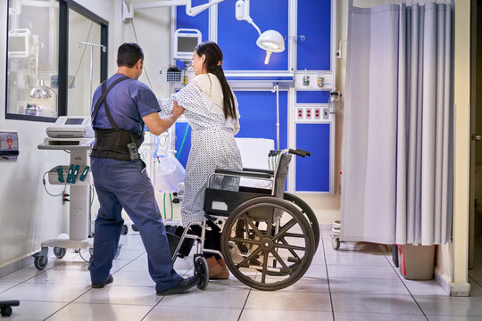 Nurse assistant helping young woman out of her wheel chair