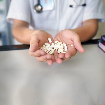 Pharmacy concept photo of doctor showing a large amount of pills in his hands 