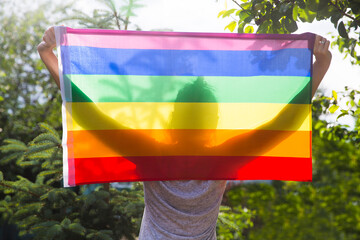 woman holding gay pride flag in countryside. Rainbow LGBT flag.
