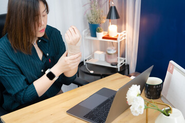 asian businesswoman hand and wrist pain during use computer in office long time