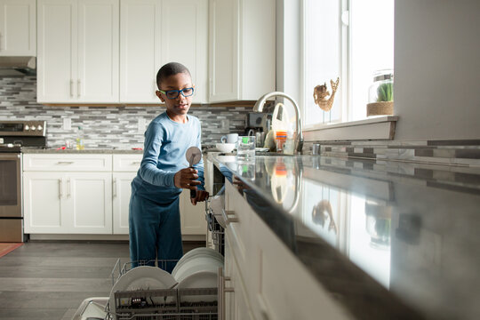 Black boy puts pizza cutter into dishwasher