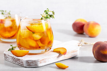 iced carbonated tea with peaches and mint in a glass on a gray background, horizontal