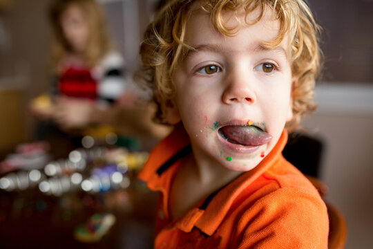 Boy licks frosting and sprinkles from his messy face