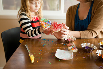 Mother and daughter hold up decorated heart sugar cookies