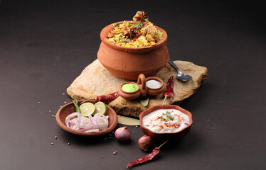  Spicy chicken dum biryani in traditional handi or clay pot. served with onion raita