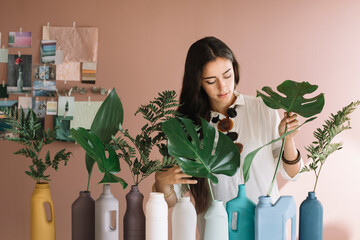 Young Woman Putting Leaves in Colored Plastic Bottles 