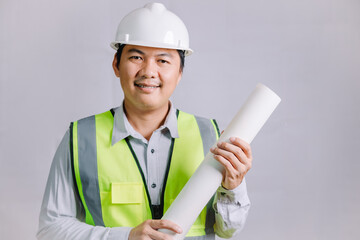 A young architect or engineer wearing a reflective vest and safety helmet in construction work, a young professional architect holding a blueprint for his design work.