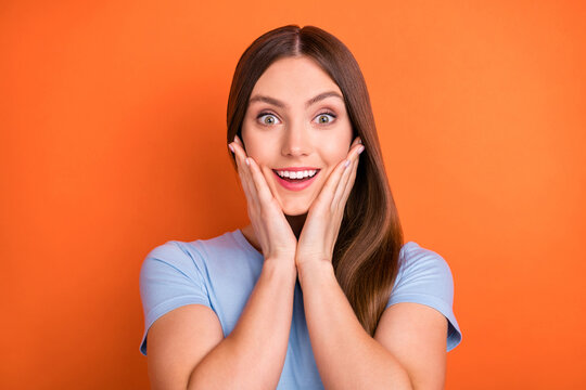 Photo of impressed brown hairdo millennial lady hands face wear blue t-shirt isolated on vivid orange color background