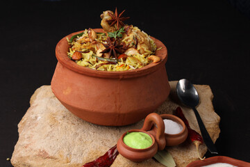  Spicy chicken dum biryani in traditional handi or clay pot. served with onion raita