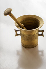 Brass mortar and pestle with mallet on the table.