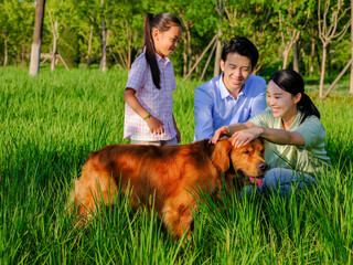 Happy family of three and pet dog playing in the park