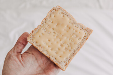 Hand holding bread with sweetened condensed milk on top. Easy dessert.