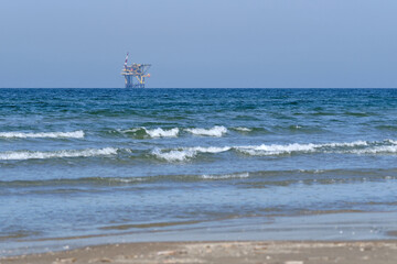 Ameland,Netherlands April 20,2021-NAM, Oil rig, offshore platform with beach, sand and surf. Natural gas extraction in the Wadden-North Sea Region, Wadden Island, nature conservation area:Het Oerd.