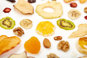 Close up of healthy food dried apples, orange, dried apricots, kiwi, dried coconut and walnuts on white background. Concept of proper nutrition with tasty of dried fruits and nuts.
