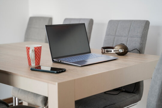 Laptop mug headphones and phone on top of table in living room in home office