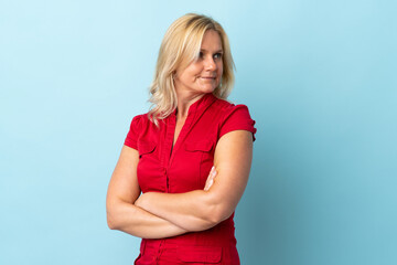 Middle age woman isolated on blue background with arms crossed and happy