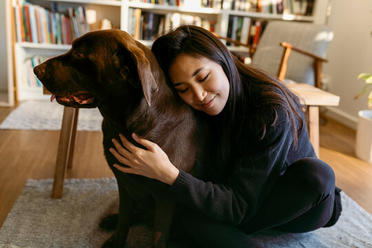 female east asian woman and her labrador dog at home