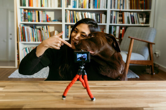 female east asian woman and her labrador dog at home recording a video