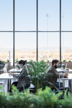 Male and female passengers against window in airport cafeteria