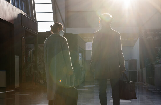 Travelers standing in airport terminal in sunlight