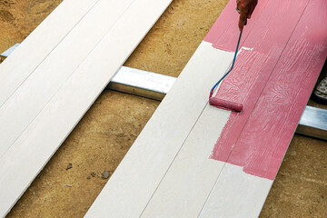Painting artificial wood board white with a small roller .