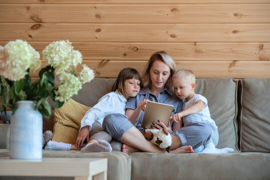 Woman showing tablet to curious boy and girl
