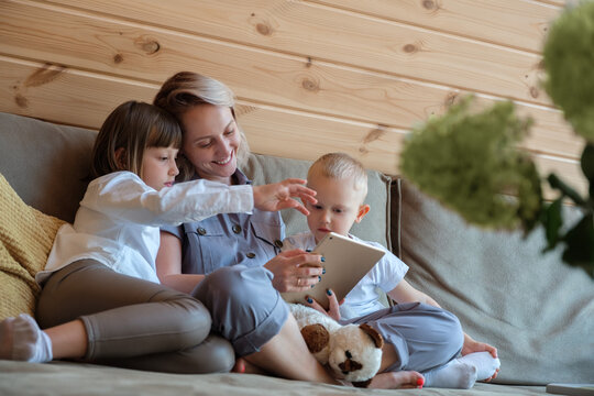 Delighted mother and kids browsing data on tablet together