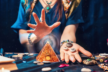 Astrology and magic. A fortune teller holds stones with the sign of the zodiac in her hands and conjures a magic pyramid. Close up. The concept of horoscopes and stories