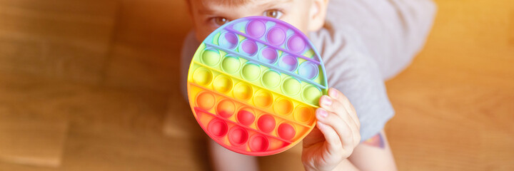 anti stress sensory pop it toys in a children's hands. a little happy kid boy plays with a simple...