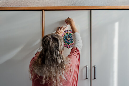  Woman hanging a mandala painting at room