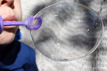 young boy blowing bubbles from bubble maker close up view