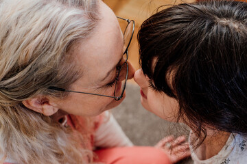 Portrait of grandmother and granddaughter looking each other with tenderness 