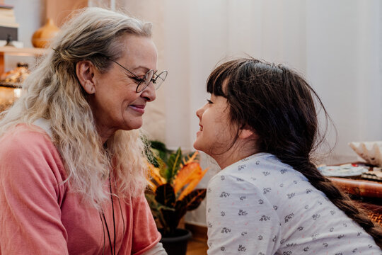 grandmother having fun with her granddaughter at bedroom 